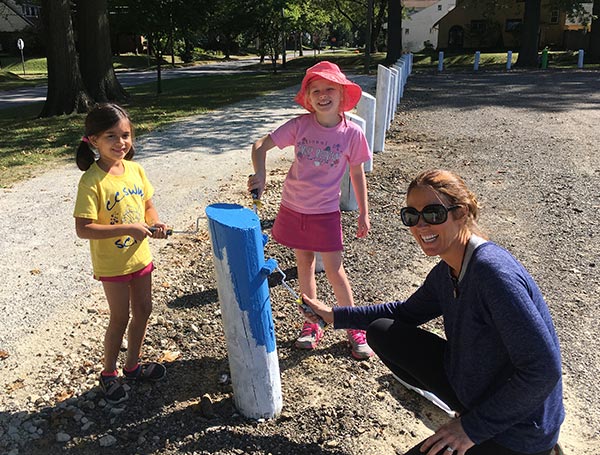 lady and kids painting poles